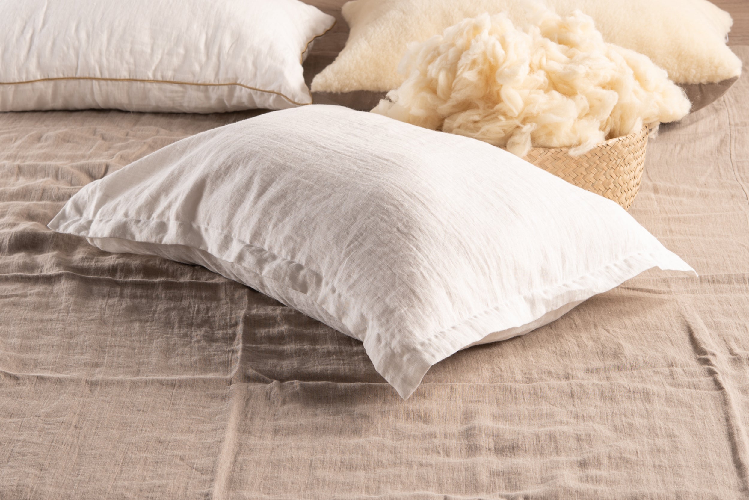 Natural linen Oxford style pillowcase with elegant decorative stitching placed on a bed next to fluffy filling.